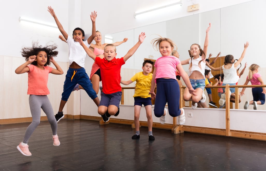 Happy sporty kids jumping together in dance studio